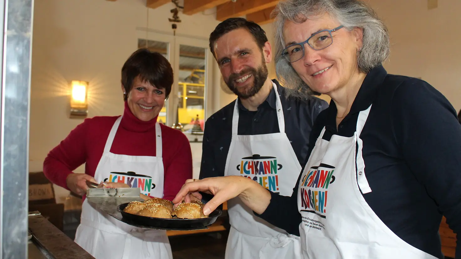 Teilnehmer der Genussbotschafterschulung ziehen Vollkornbrötchen aus einem Backofen.