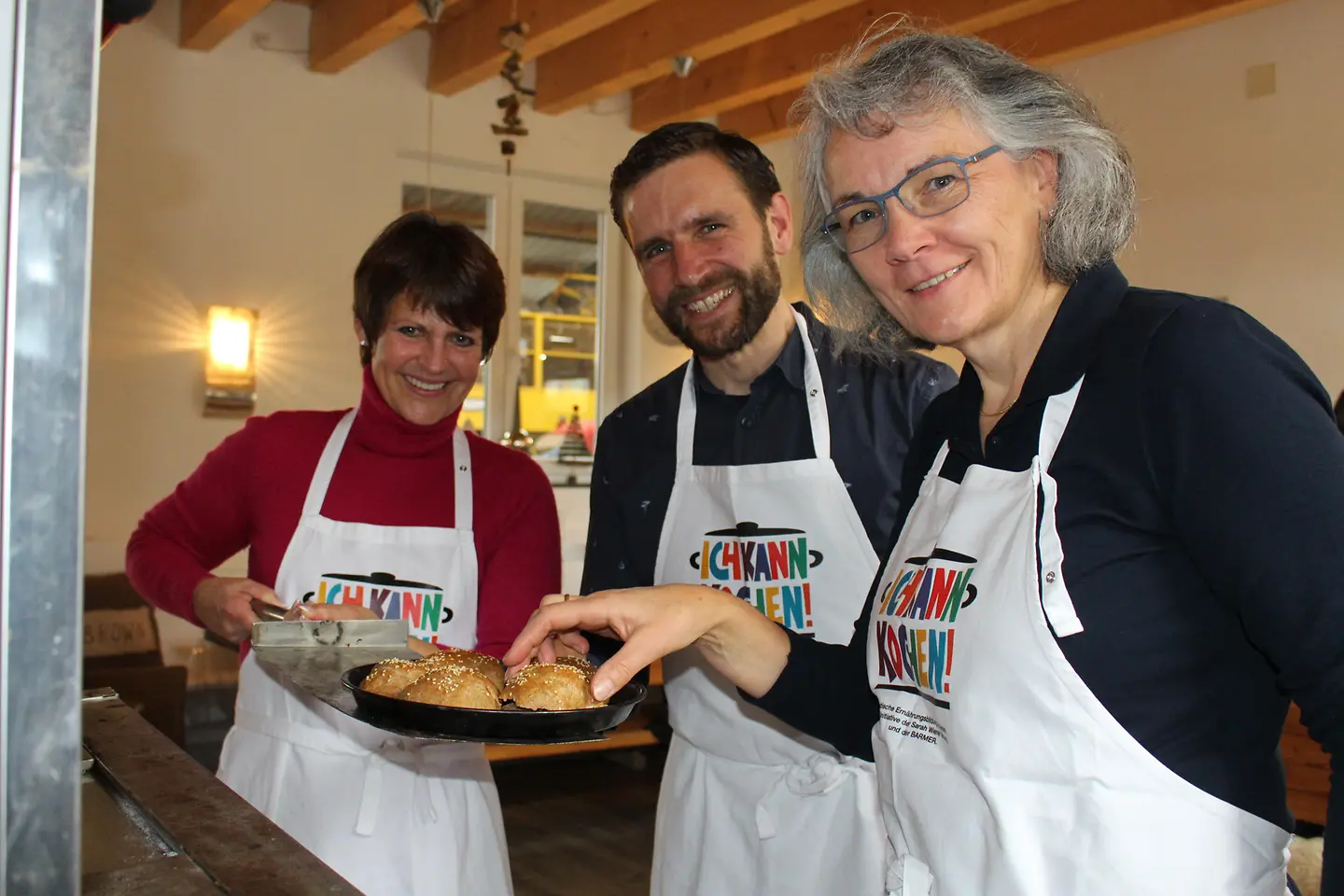 Teilnehmer der Genussbotschafterschulung ziehen Vollkornbrötchen aus einem Backofen.