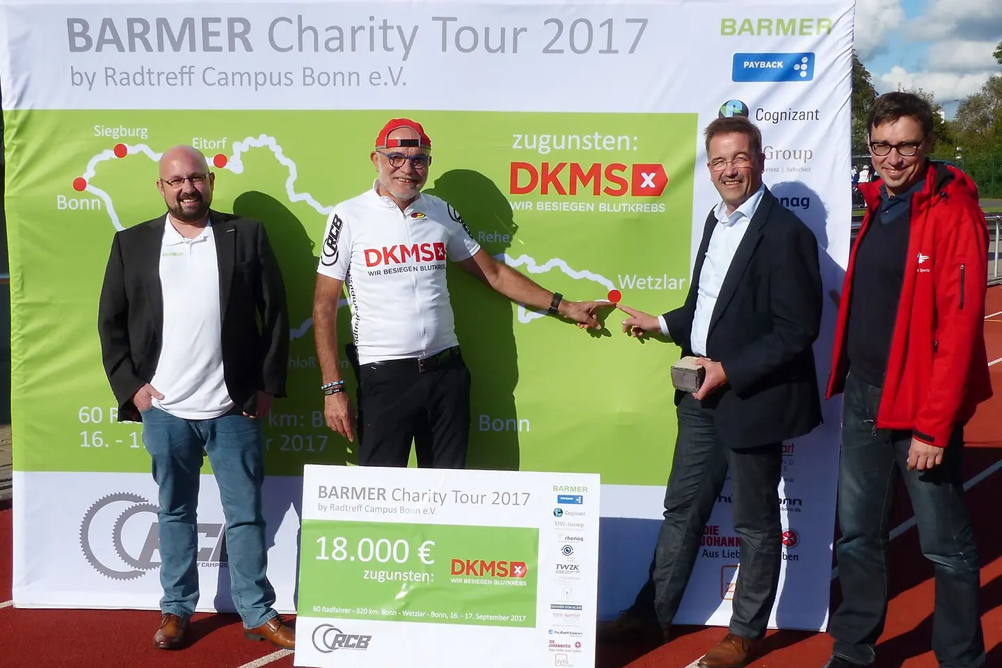 Vier Personen bei Scheckübergabe