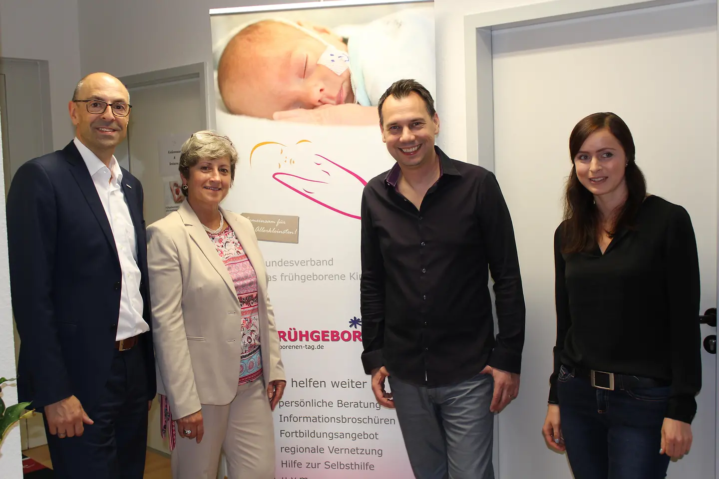 Vier Personen stehen vor einem Plakat