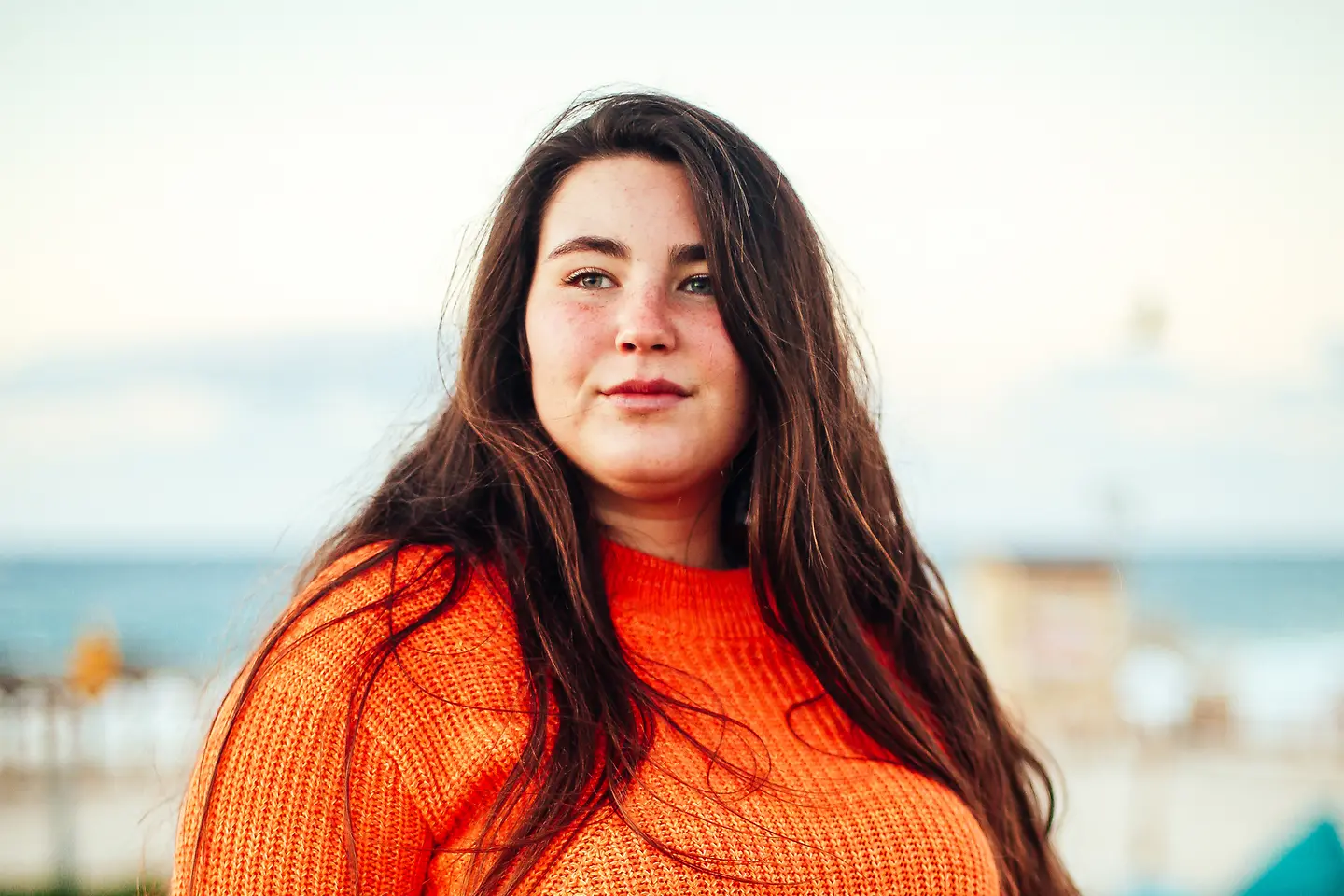 Porträt einer jungen Frau in einem orangefarbenem Pullover