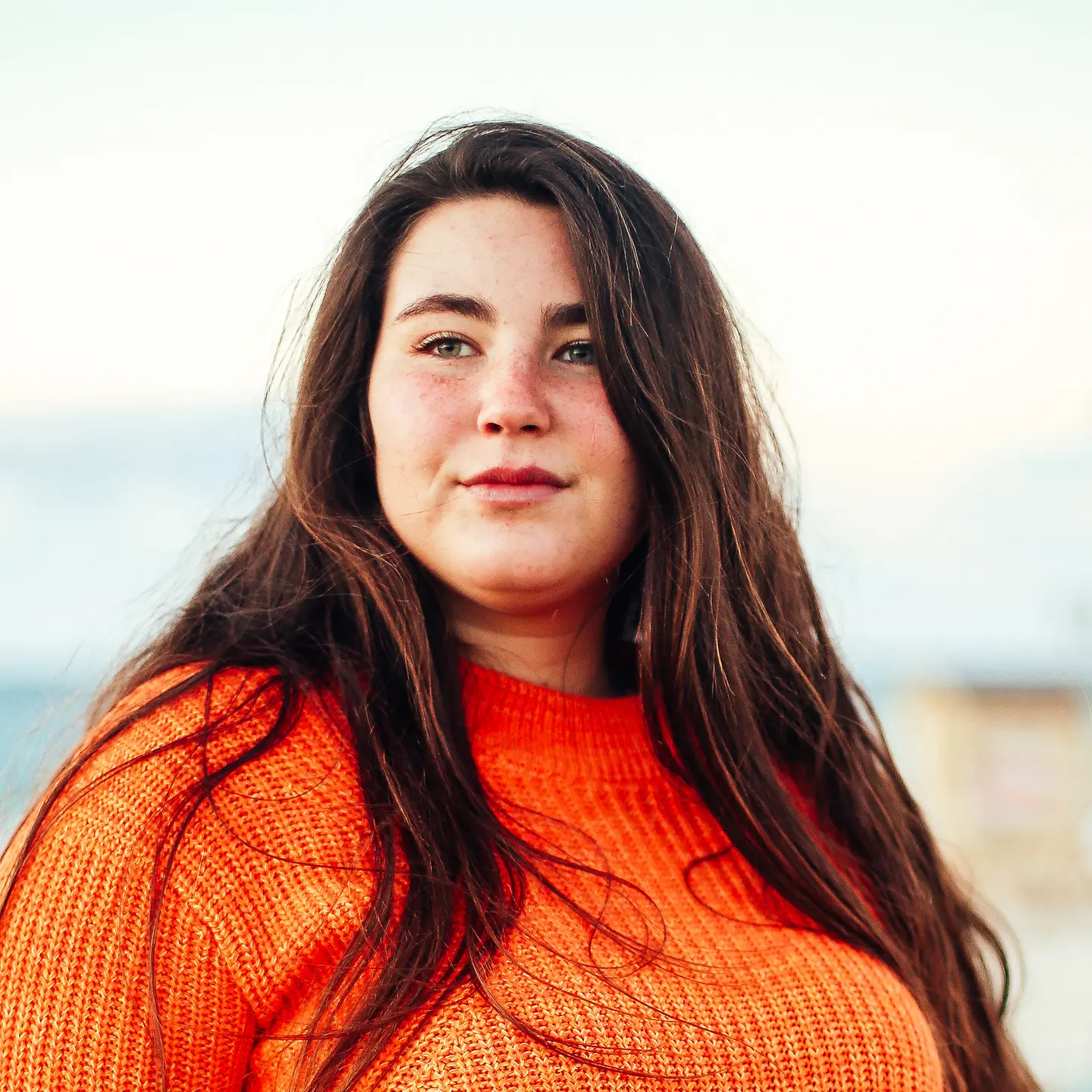 Porträt einer jungen Frau in einem orangefarbenem Pullover