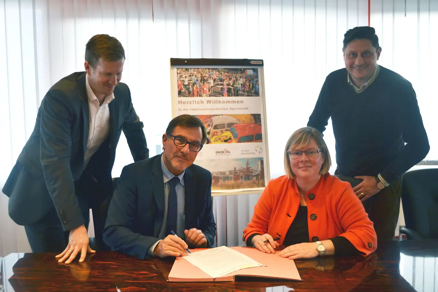 Vier Personen beim Unterschreiben eines Vertrages