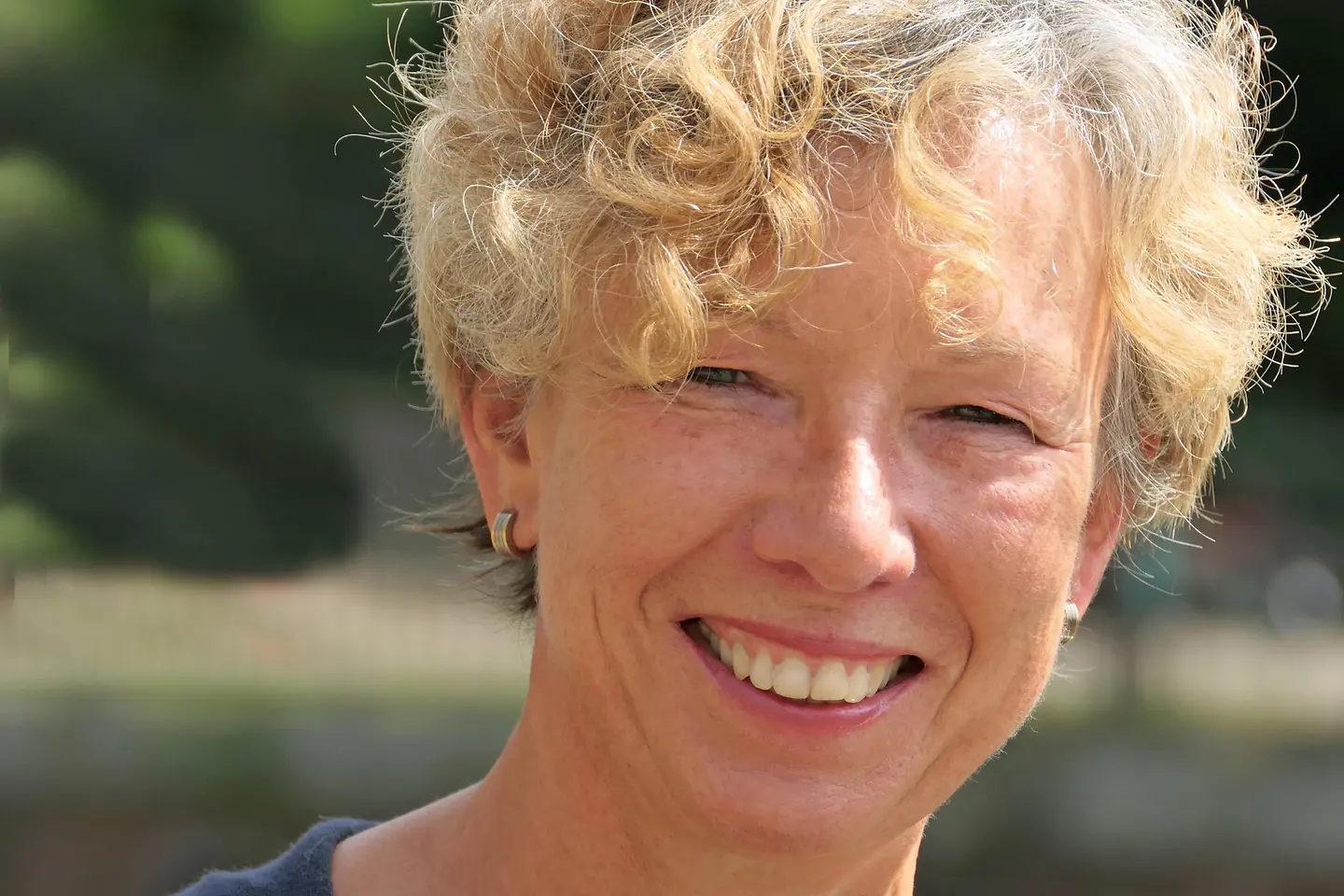 Susanne Kleins lachendes Portrait mit blonden Locken.