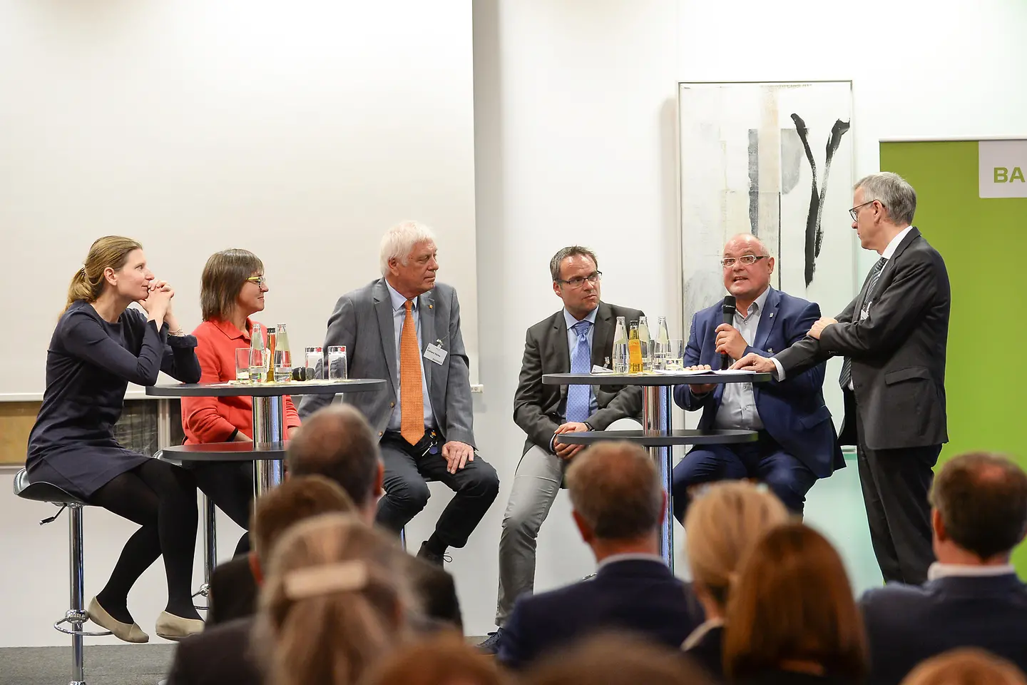 Sechs Teilnehmende sitzen auf dem Podium