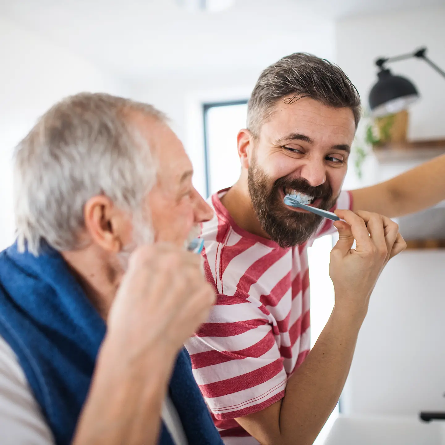 Ein junger Mann und sein Vater putzen zusammen Zähne