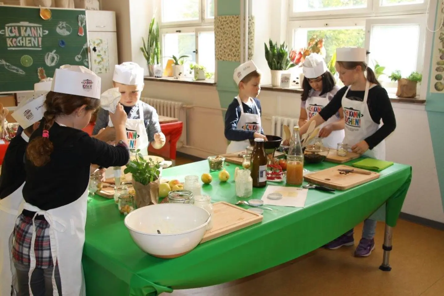 Ich kann kochen! Kinder kochen gemeinsam an einem grünen Tisch