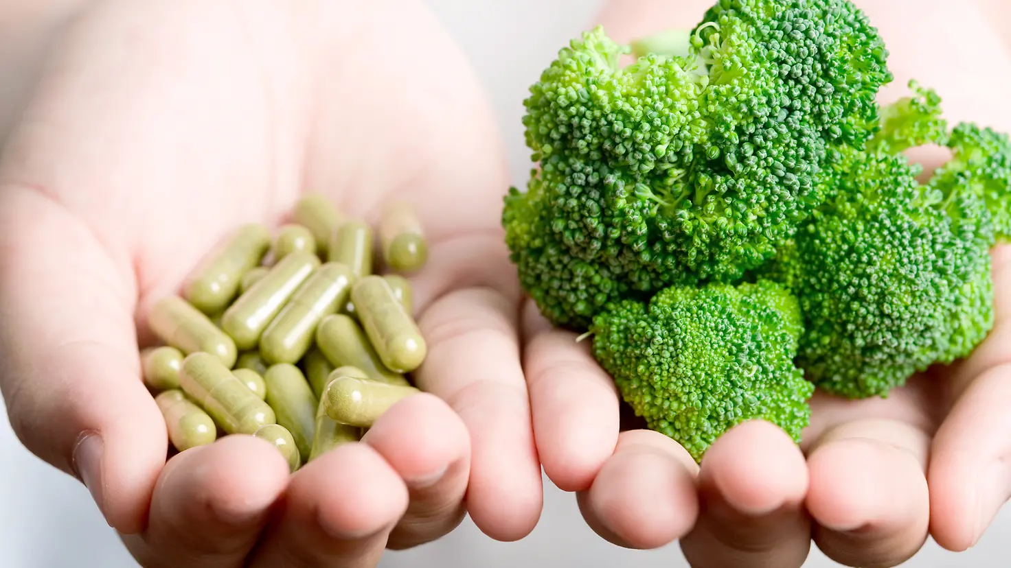Brokkoli und grüne Kapseln liegen in einer Hand