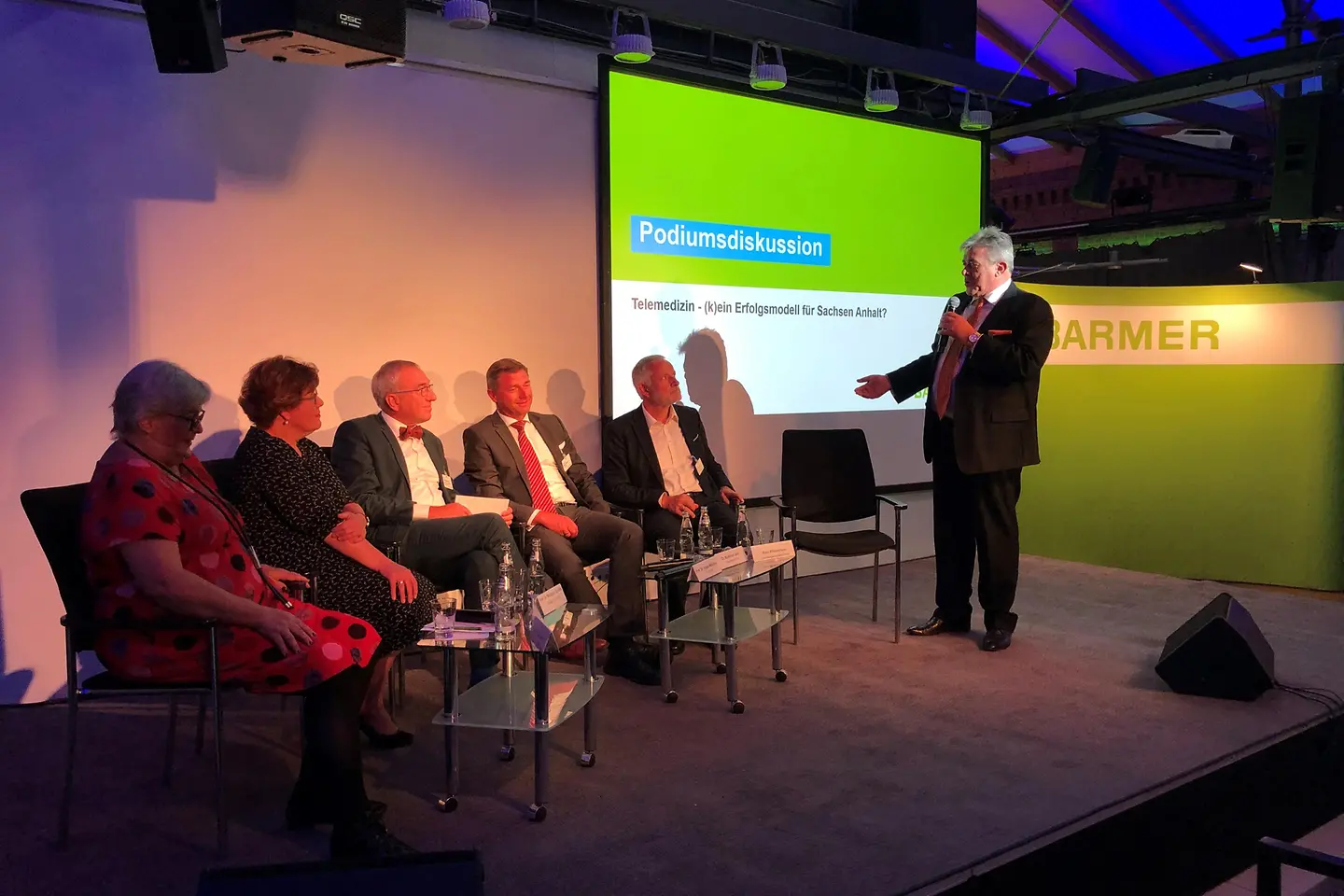 Barmer-Landesgeschäftsführer Axel Wiedemann diskutiert mit den Podiumsteilnehmern.