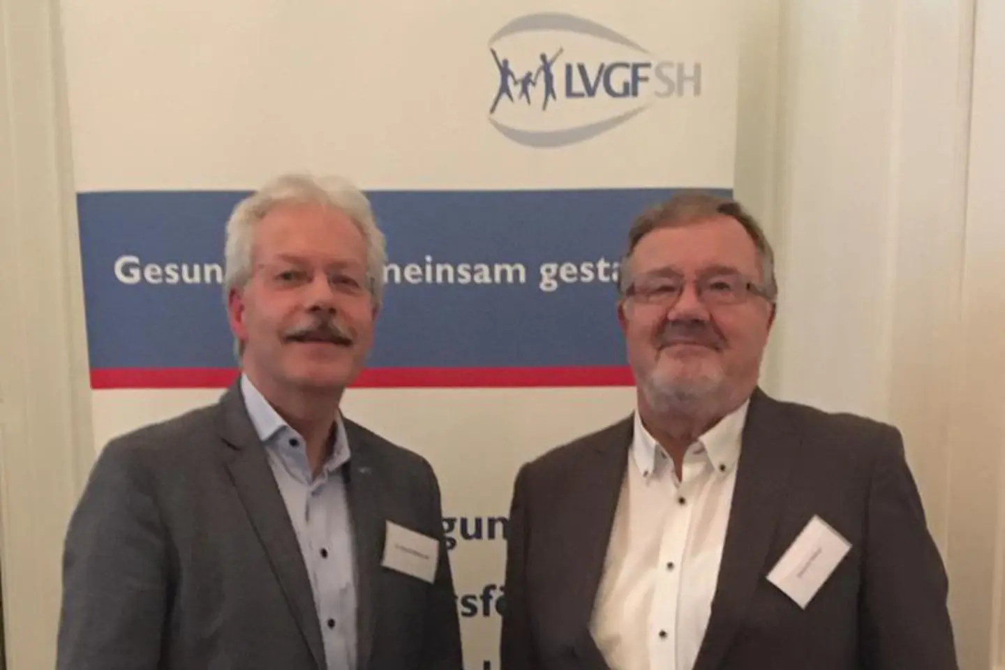 Dr. Bernd Hillebrandt und Dietmar Katzer stehend vor einem Display der LVGF-SH