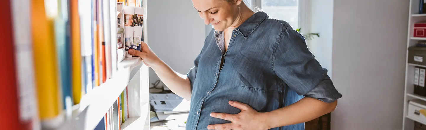Eine schwangere Frau umfasst ihren Bauch