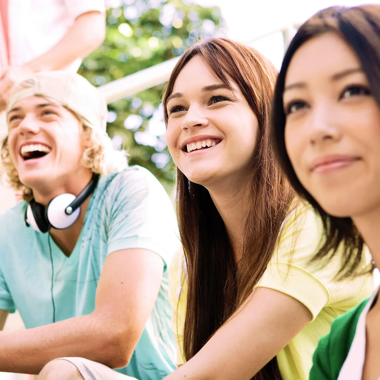 三個青少年坐在樓梯上大笑