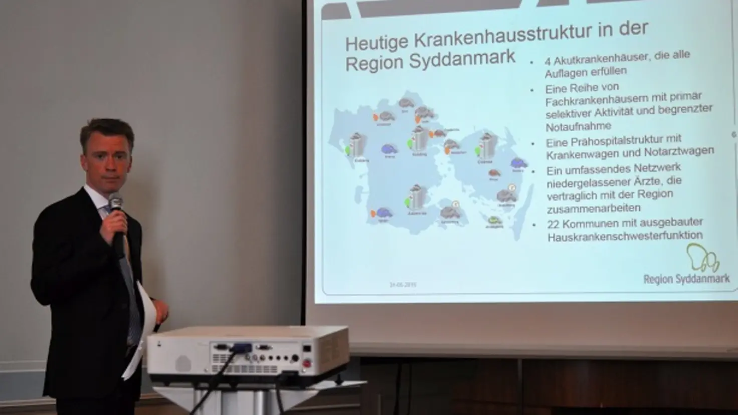 Sören Lindgaard mit Mikrofon in der Hand vor Präsentation am Whiteboard