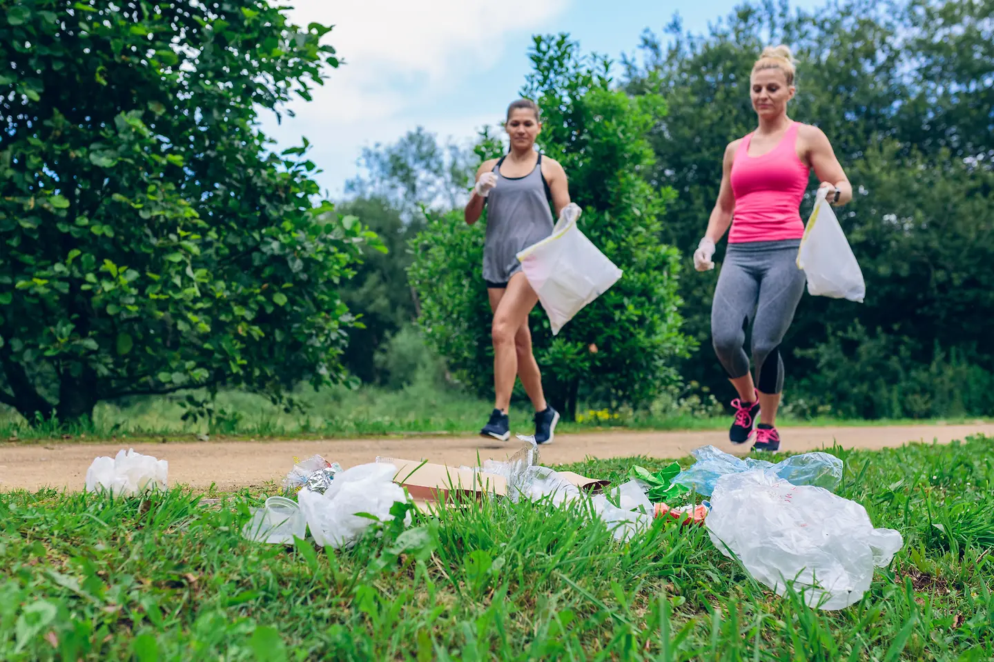 Das Bild zeigt zwei Frauen beim Joggen mit Mülltüten zum Müllsammeln.