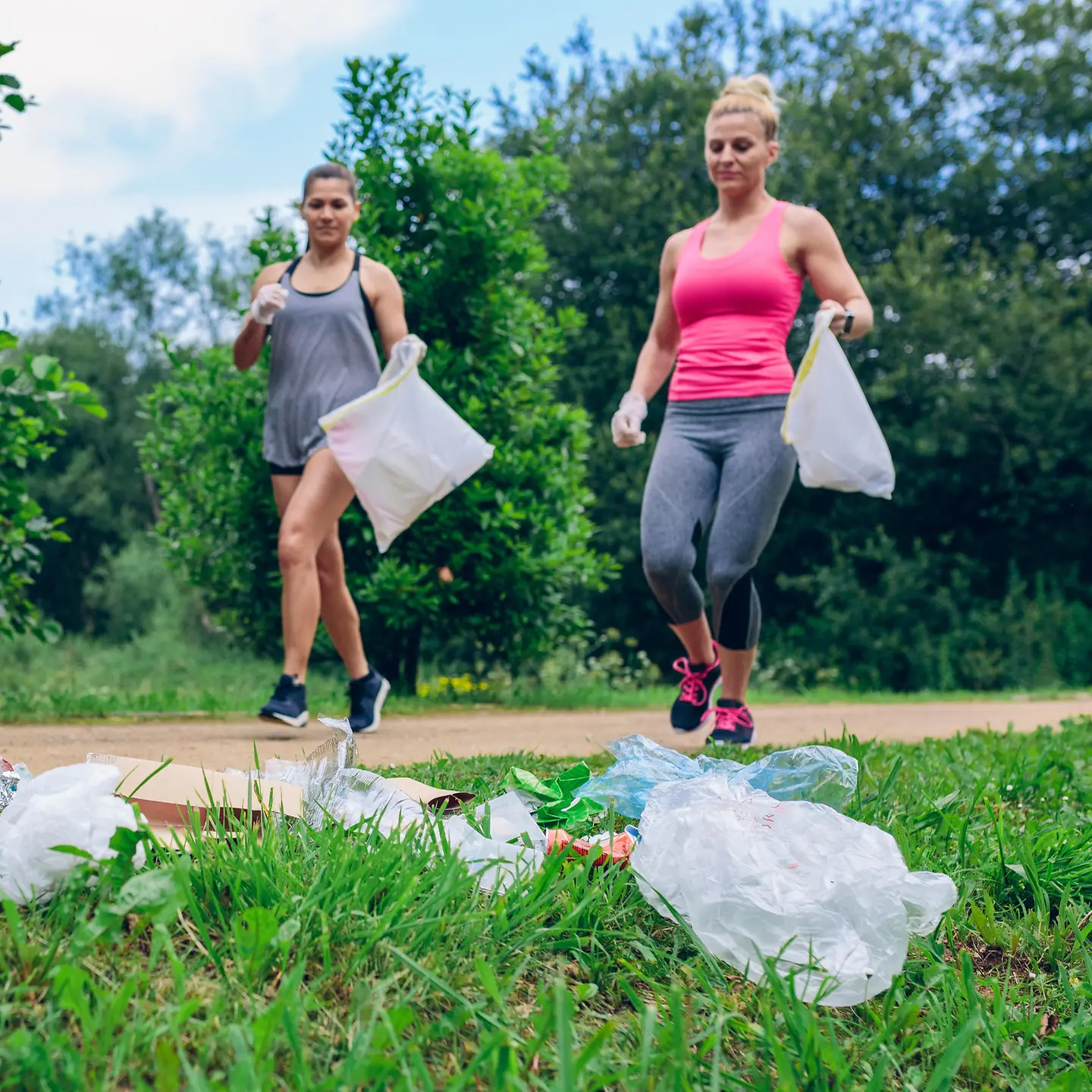 Das Bild zeigt zwei Frauen beim Joggen mit Mülltüten zum Müllsammeln.