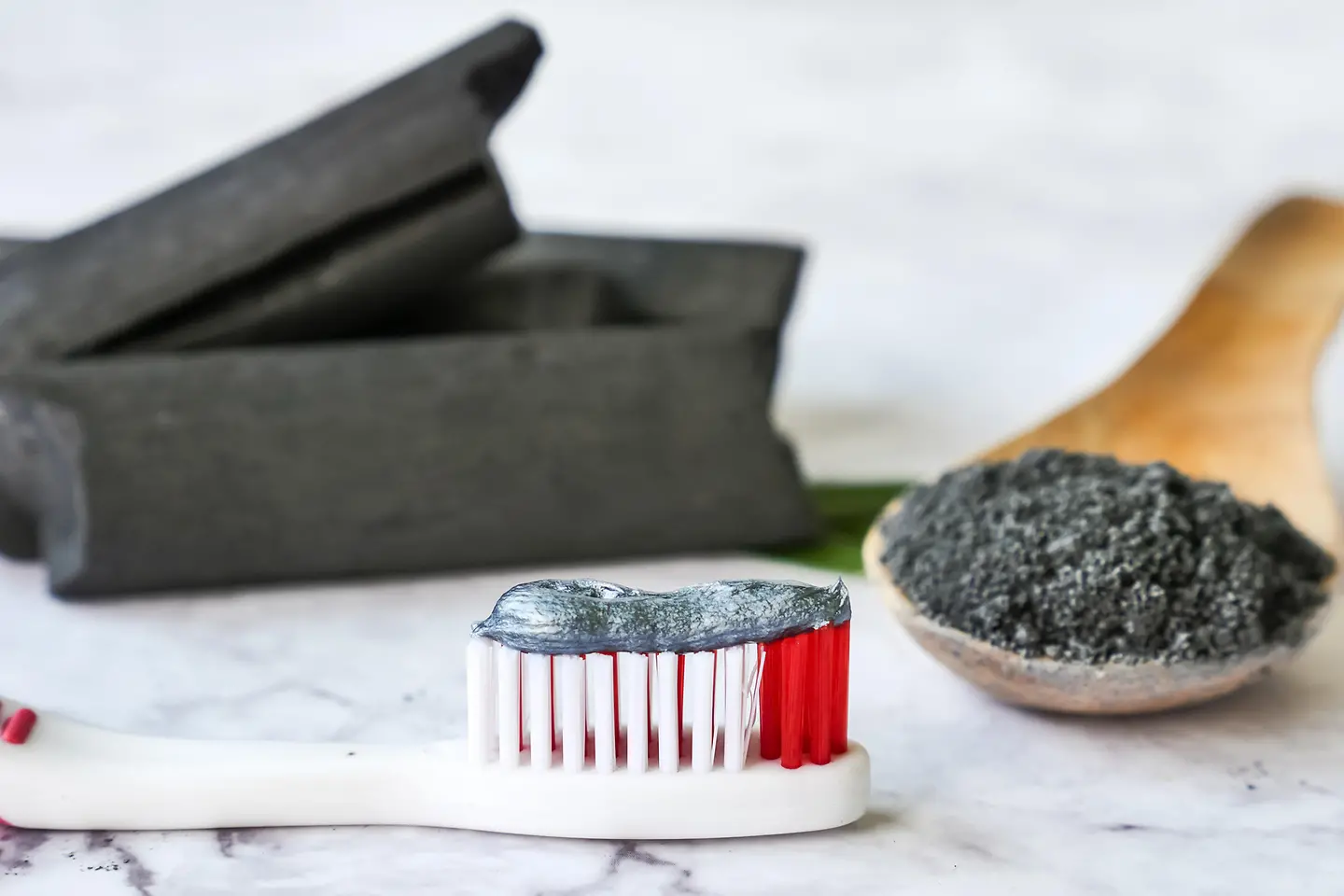 Das Bild zeigt eine Zahnbürste, auf der Aktivkohlezahnpasta aufgetragen ist.