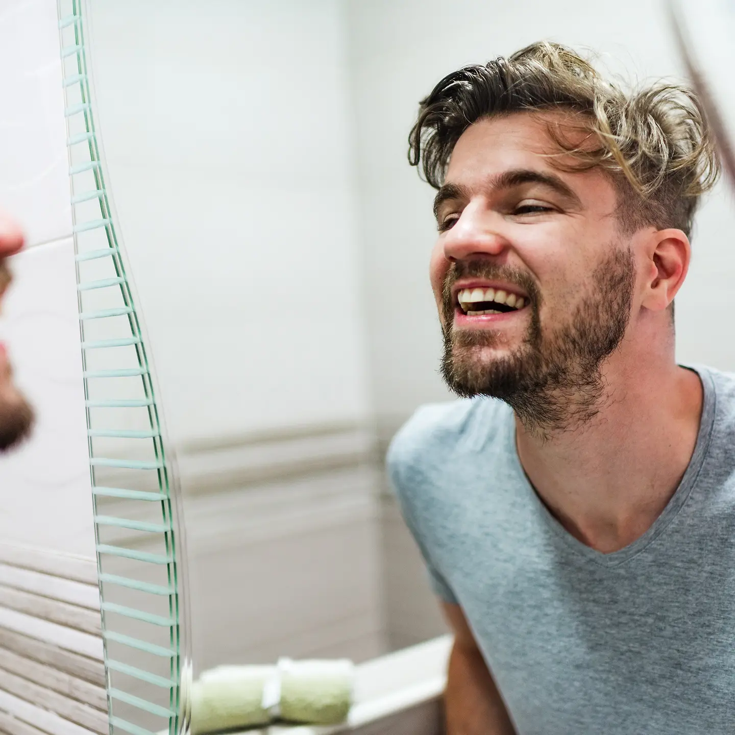 Ein Mann schaut sich im Spiegel seine Zähne an. 