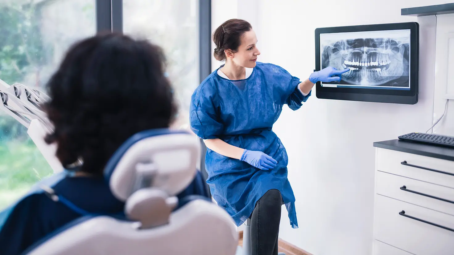Eine Zahnärztin erklärt ihrem Patienten ein Röntgenbild.