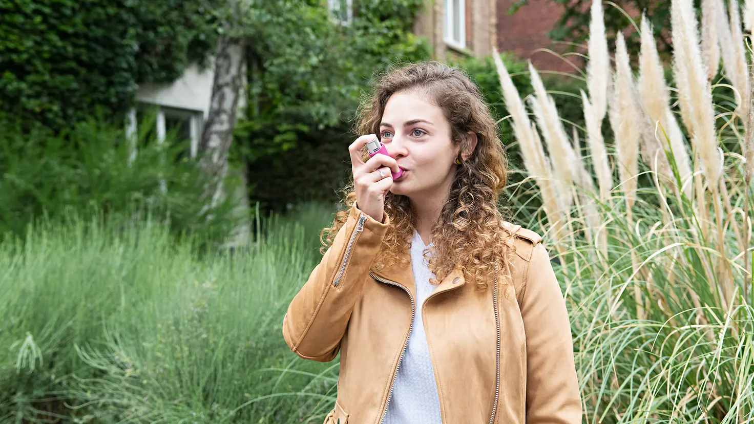 Eine junge Frau inhaliert ein Medikament gegen Asthma.