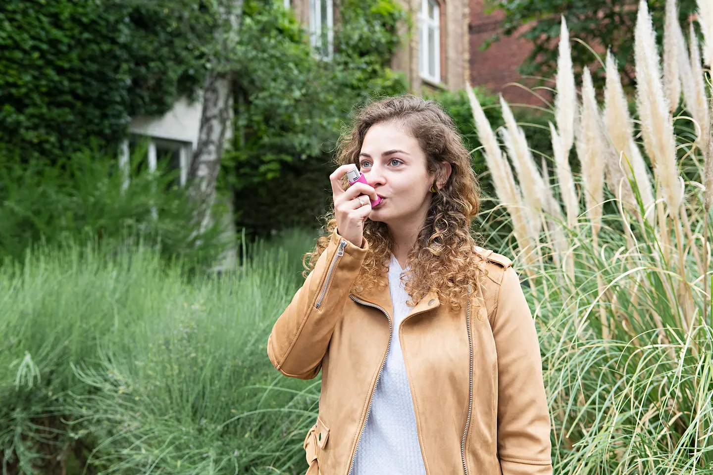 Eine junge Frau inhaliert ein Medikament gegen Asthma.