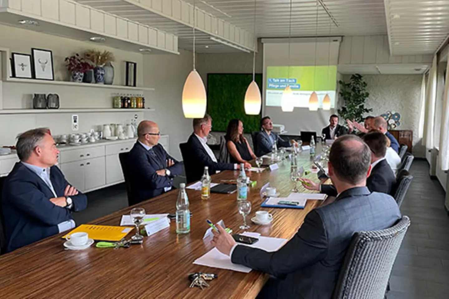 Eine Gruppe von Männern und Frauen sitzt an einem langen Tisch und diskutiert