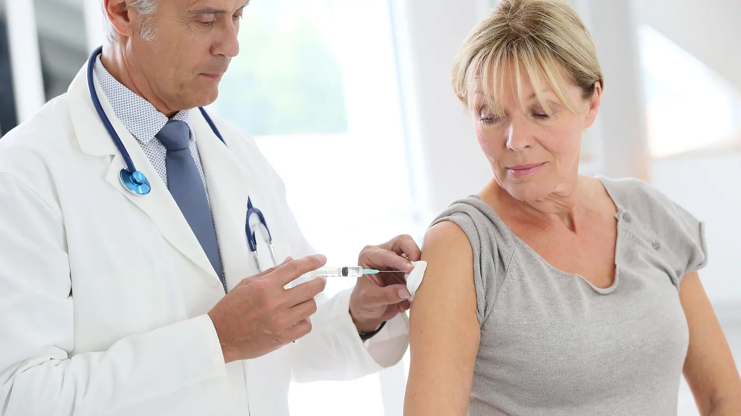 Arzt injiziert Impfstoff in den Arm eines Patienten