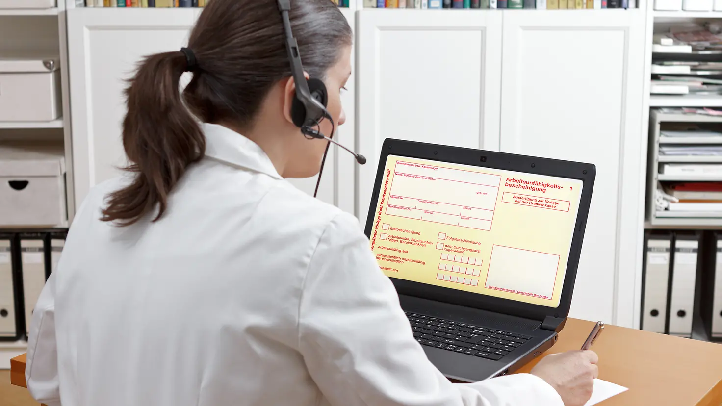 Ärztin mit Headset vor ihrem Laptop während eines Videoanrufs
