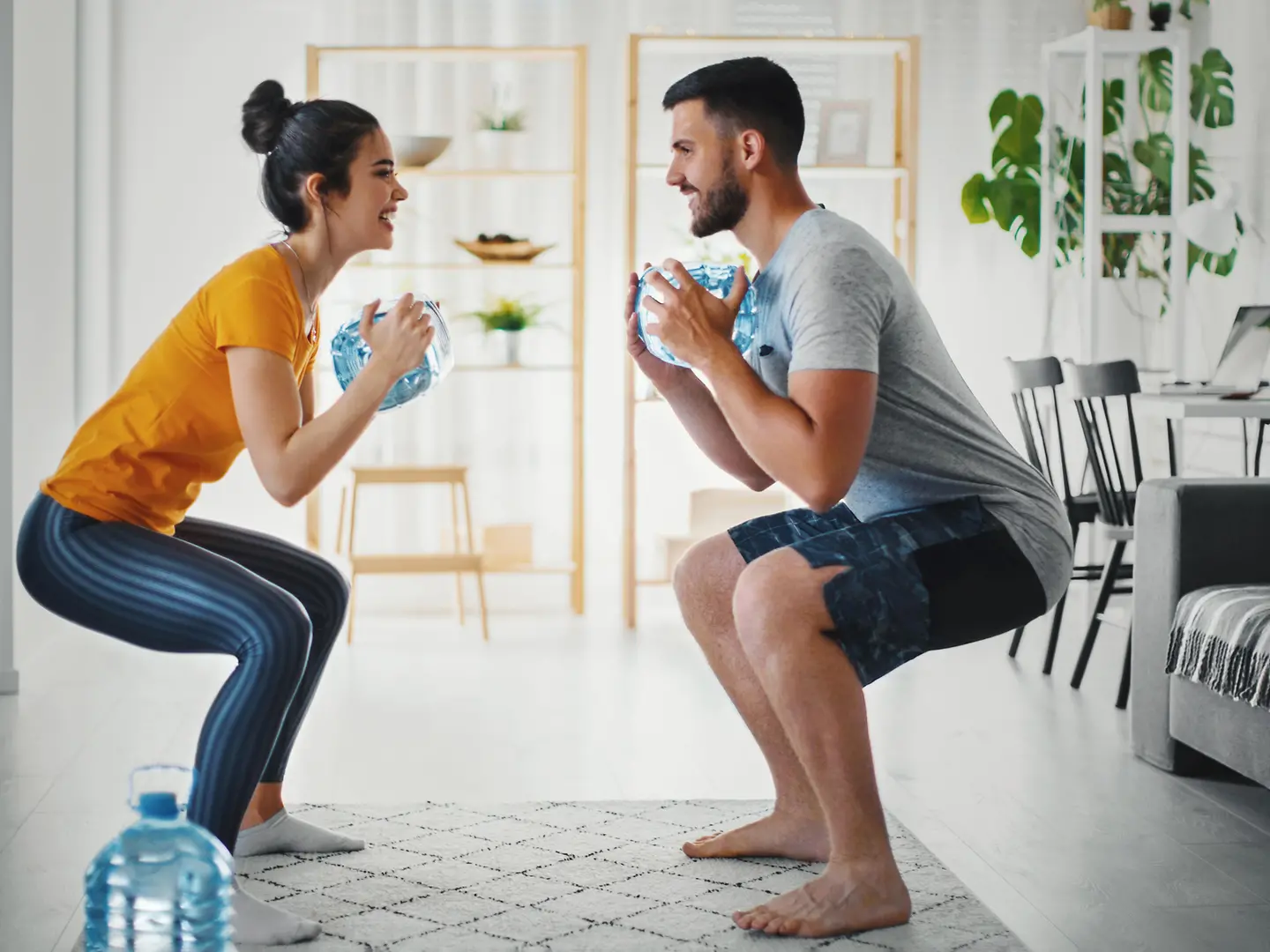 Eine Frau und ein Mann trainieren zu Hause Ihre Kraft und Ausdauer mit Wasserflaschen