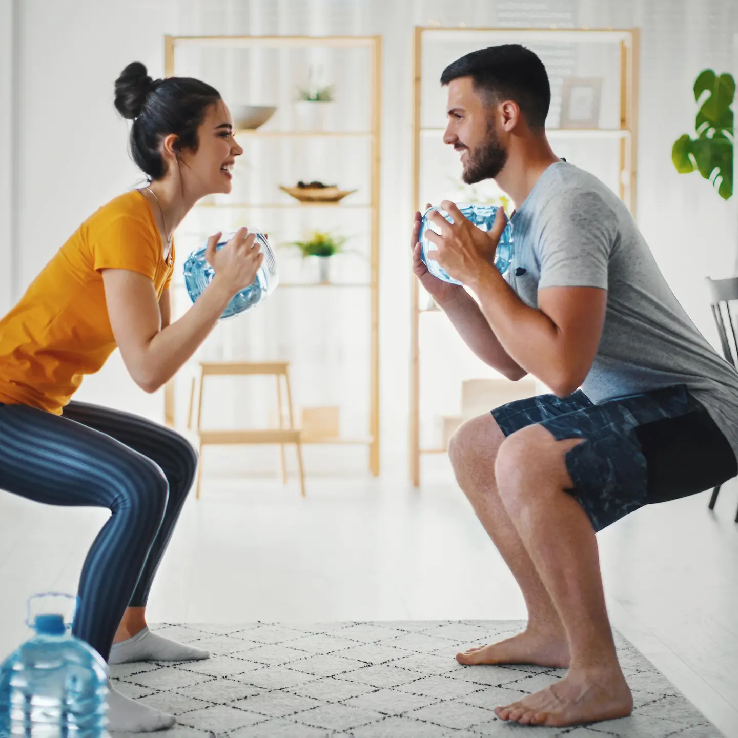 Eine Frau und ein Mann trainieren zu Hause Ihre Kraft und Ausdauer mit Wasserflaschen