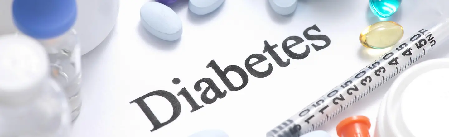 Diabetes-Schriftzug umgeben von bunten Pillen und Spritze