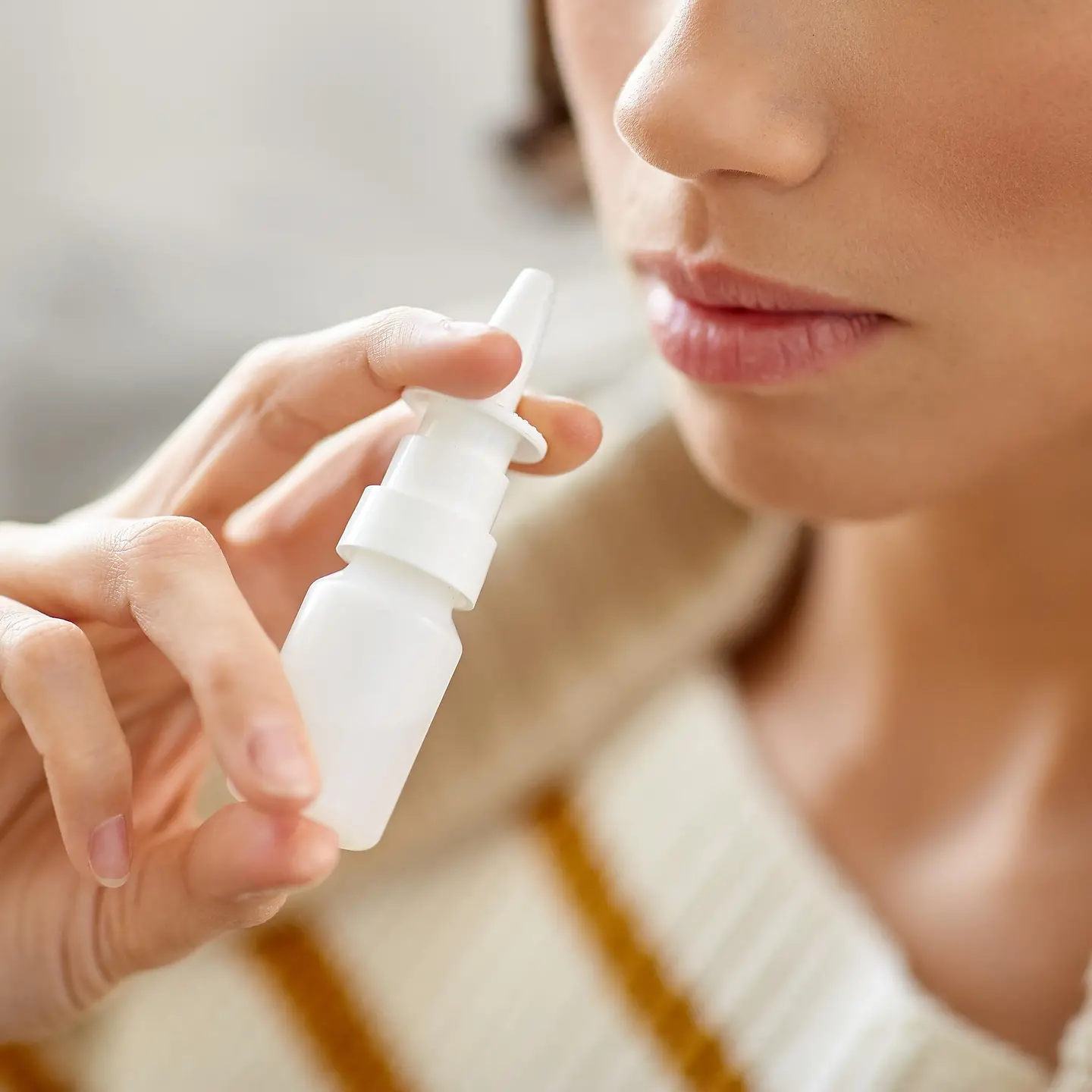 Das Bild zeigt eine Frau, die Nasenspray verwendet.