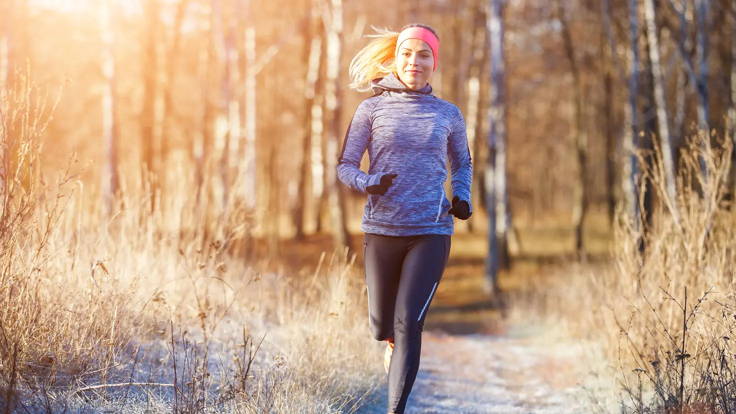 Das Bild zeigt eine Frau, die an der frischen Luft joggt.