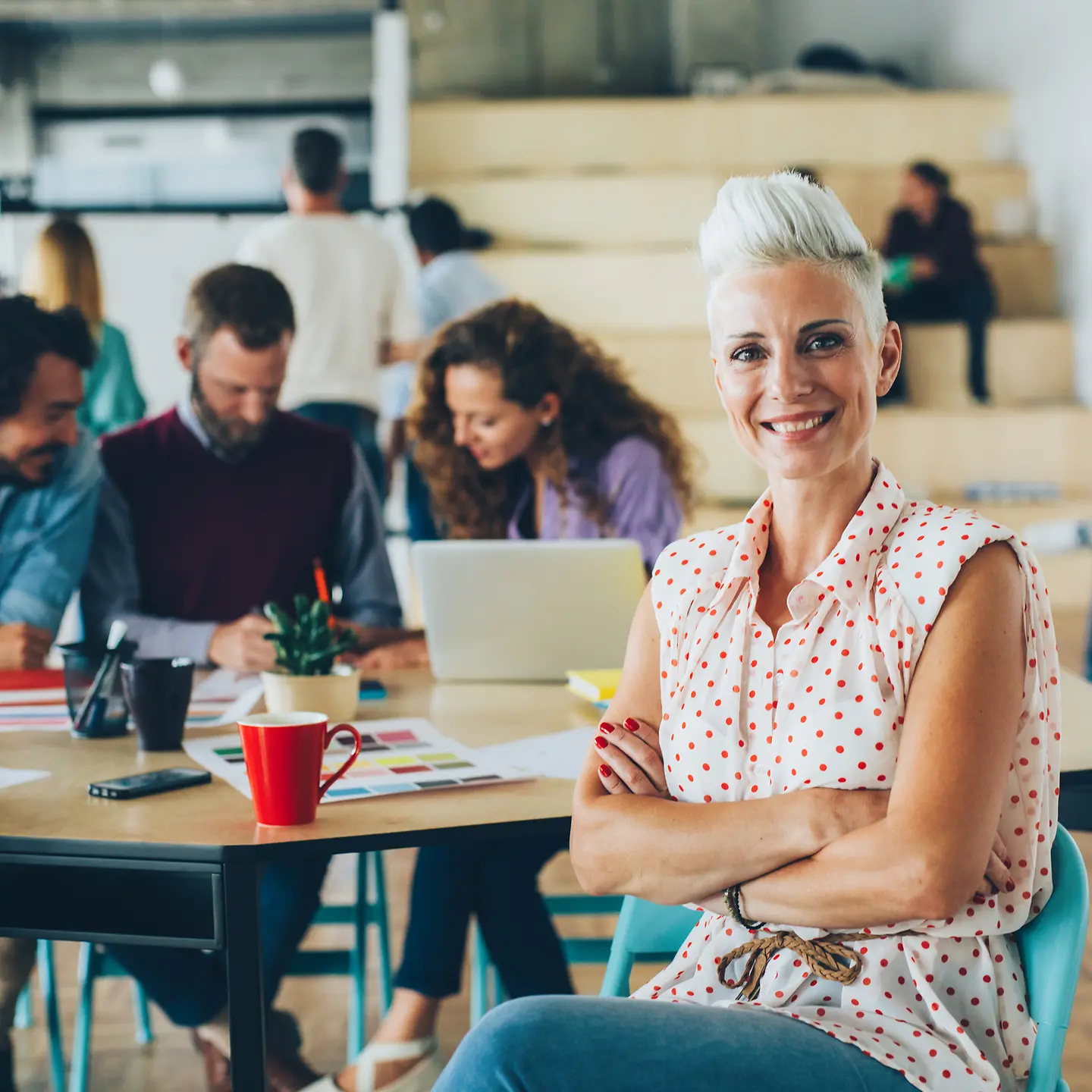 Eine Frau sitzt in einem Hochschulgebäude mit Studierenden
