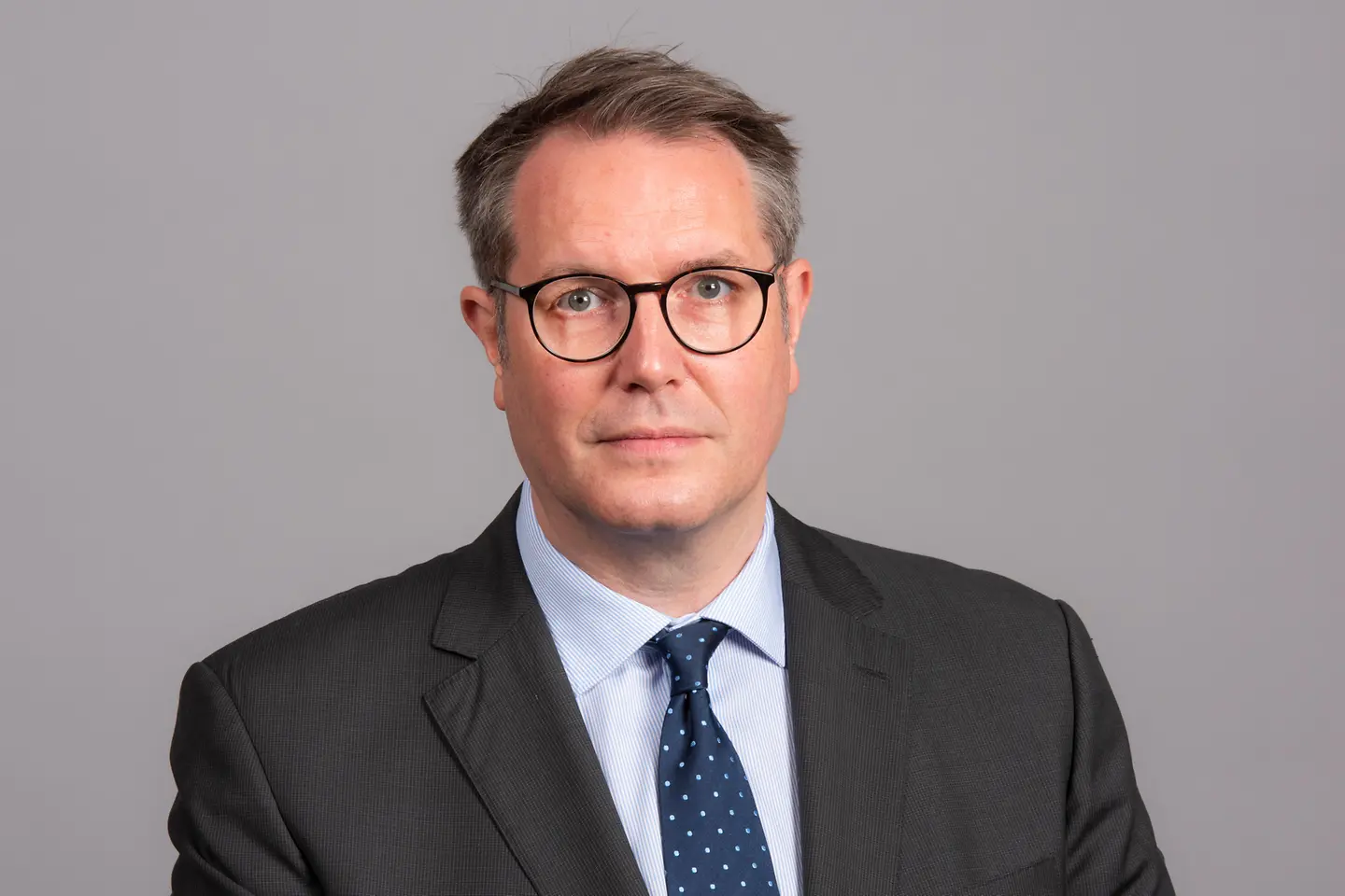 Alexander Schweitzer vor einer grauen Wand.