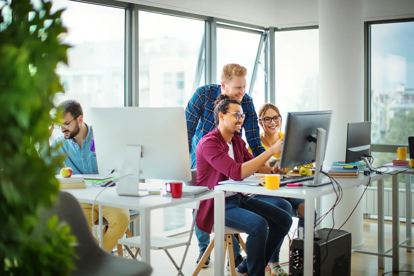 Zwei Männer und eine Frau im Büro blicken auf einen Monitor
