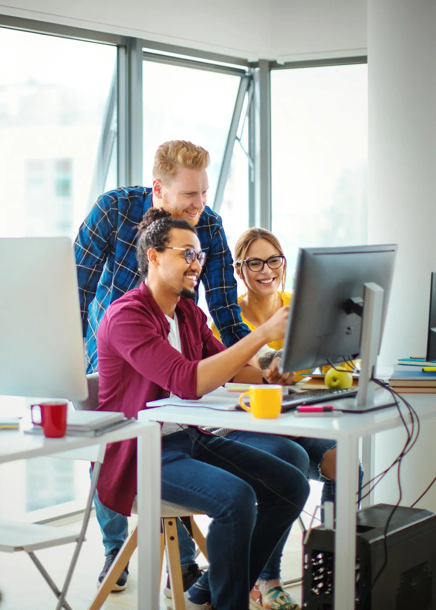 Zwei Männer und eine Frau im Büro blicken auf einen Monitor