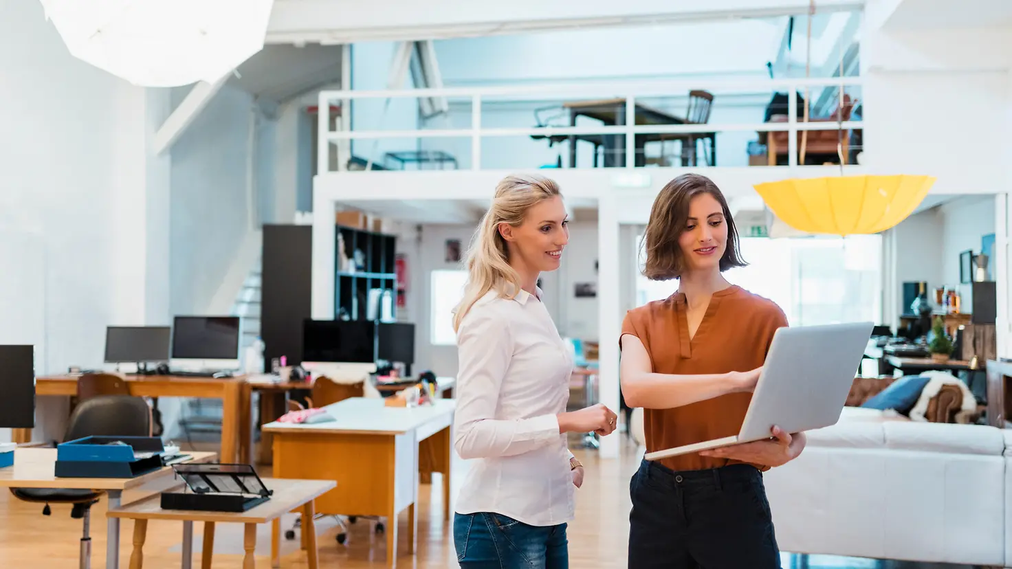 Zwei Frauen im Büro blicken auf einen Laptop