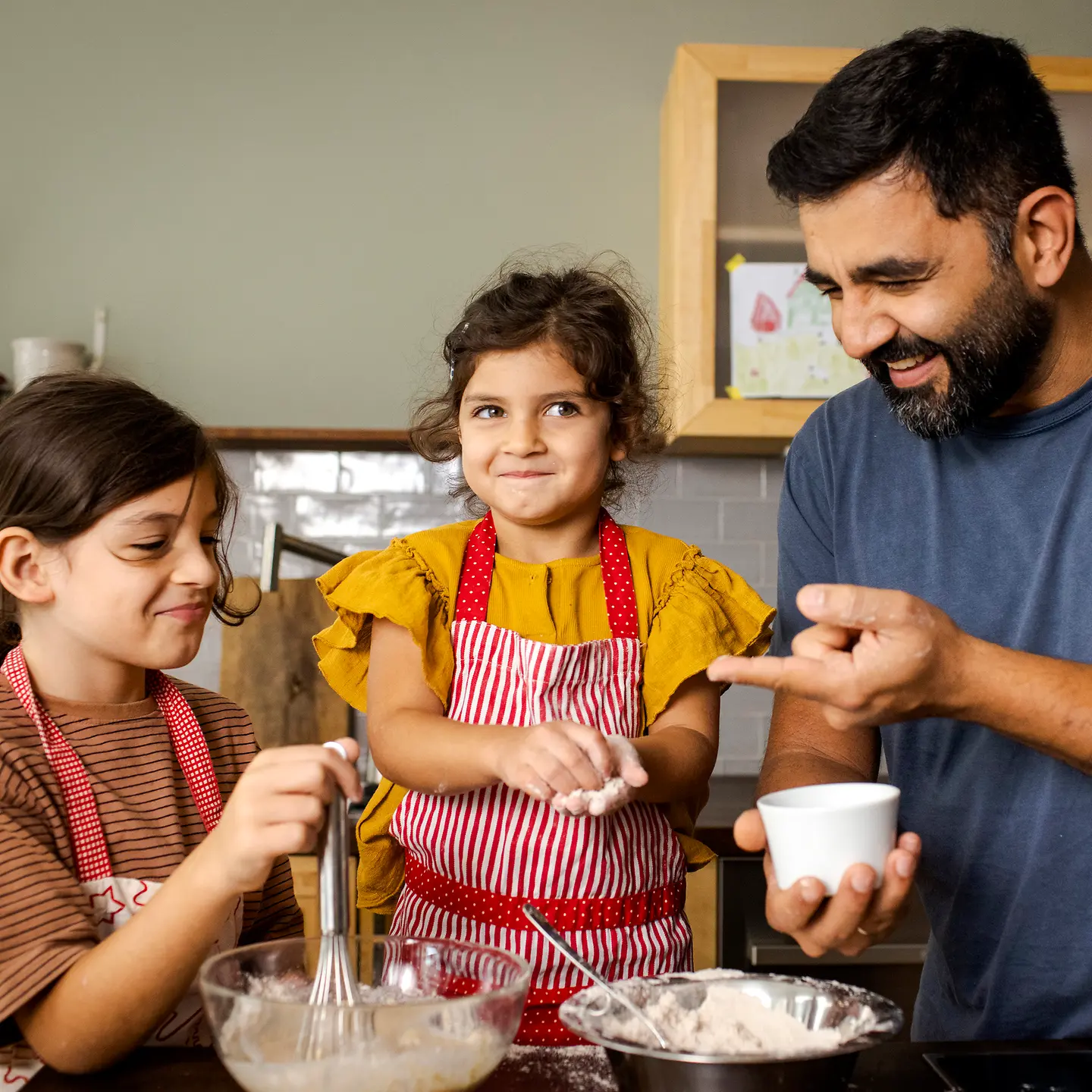 Ein Vater und seine zwei Töchter rühren zusammen Teig an