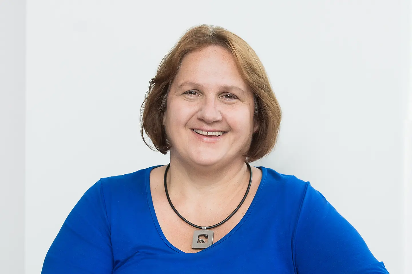 Eine Frau mit Pagenschnitt schaut in die Kamera und lächelt