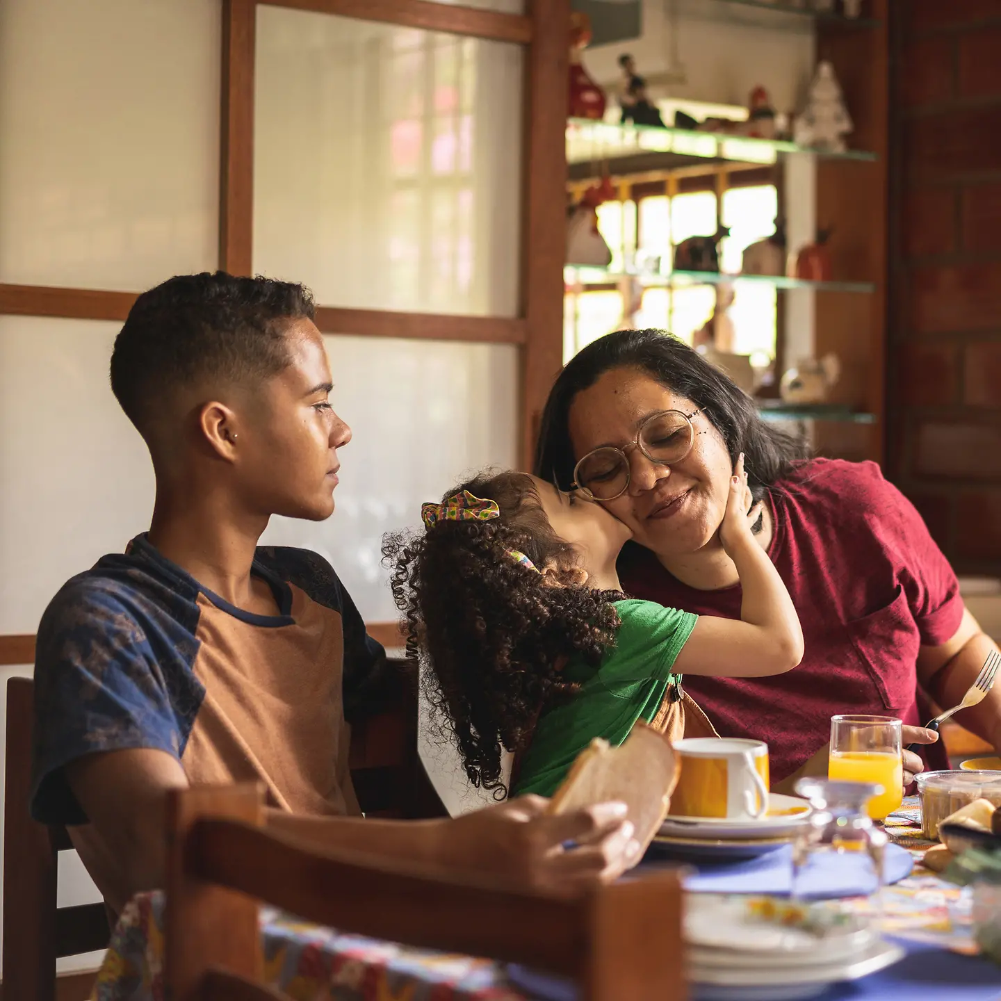 Eine Frau, ein Junge und ein Mädchen sitzen am gedeckten Frühstückstisch