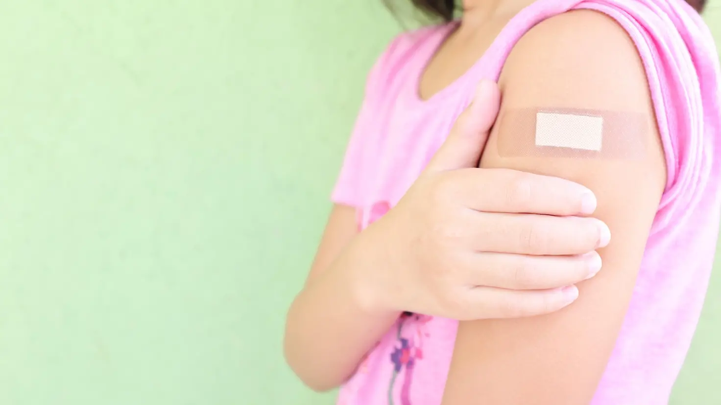 Ein Kind hat nach einer Impfung ein Pflaster am Oberarm.