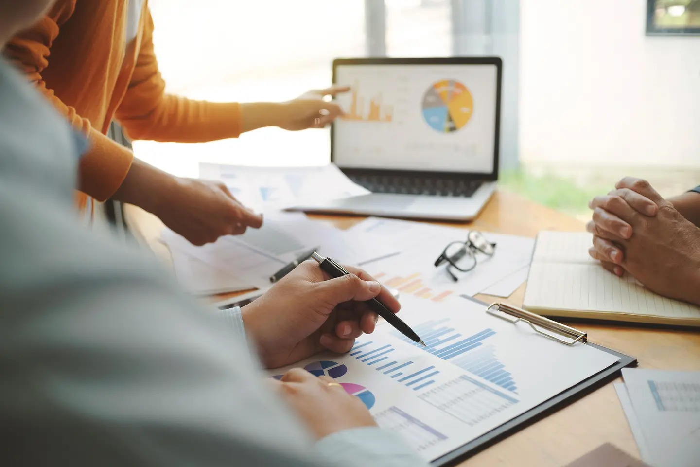 Mehrere Personen sitzen an einem Tisch und besprechen Grafiken, die vor ihnen liegen.