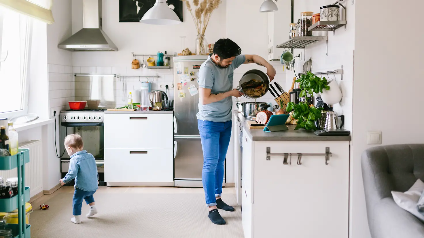 Asiatischer Mann mit seinem Kind in der Küche beim Suppe kochen