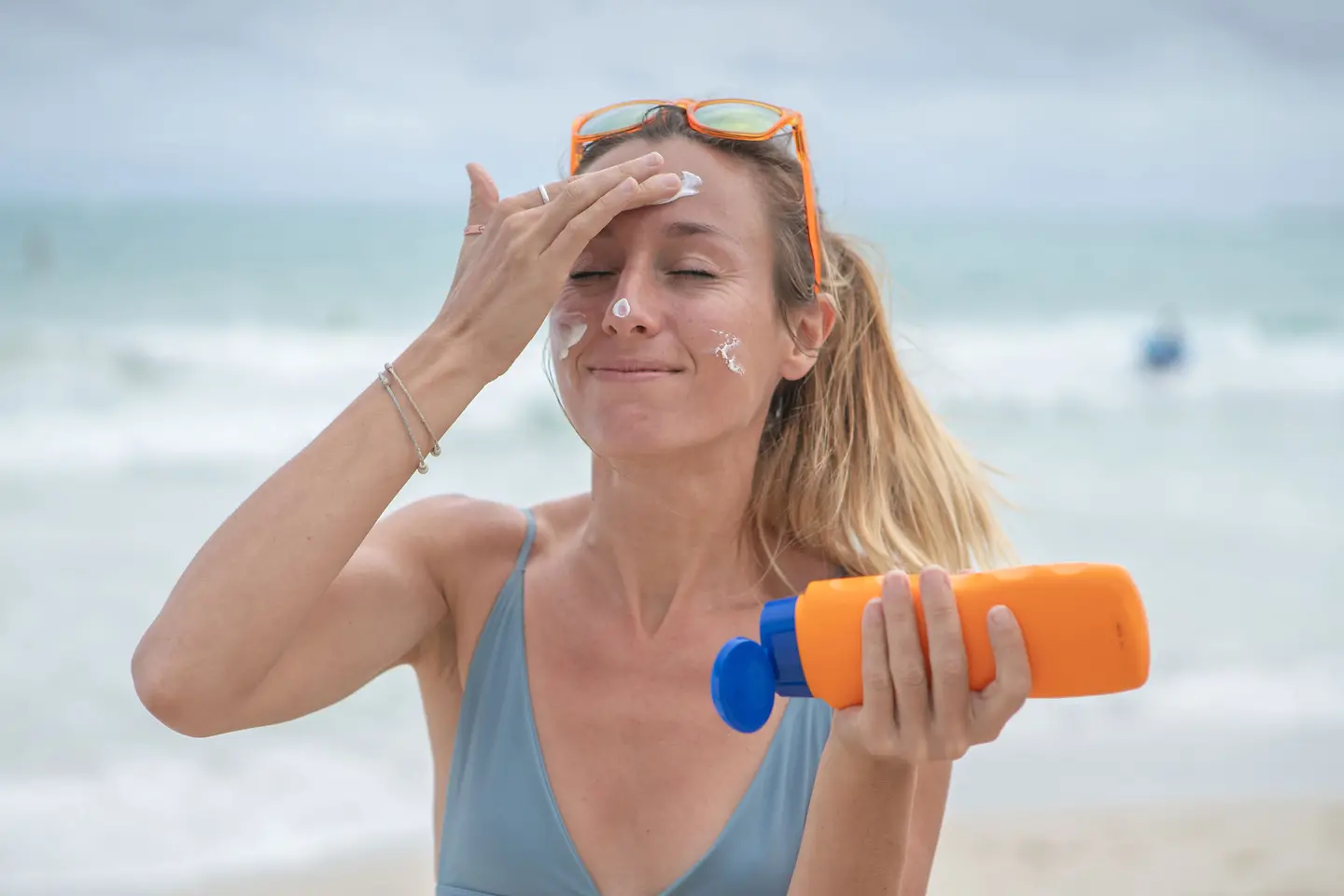 Junge Frau am Strand mit Sonnencreme auf ihrem Gesicht