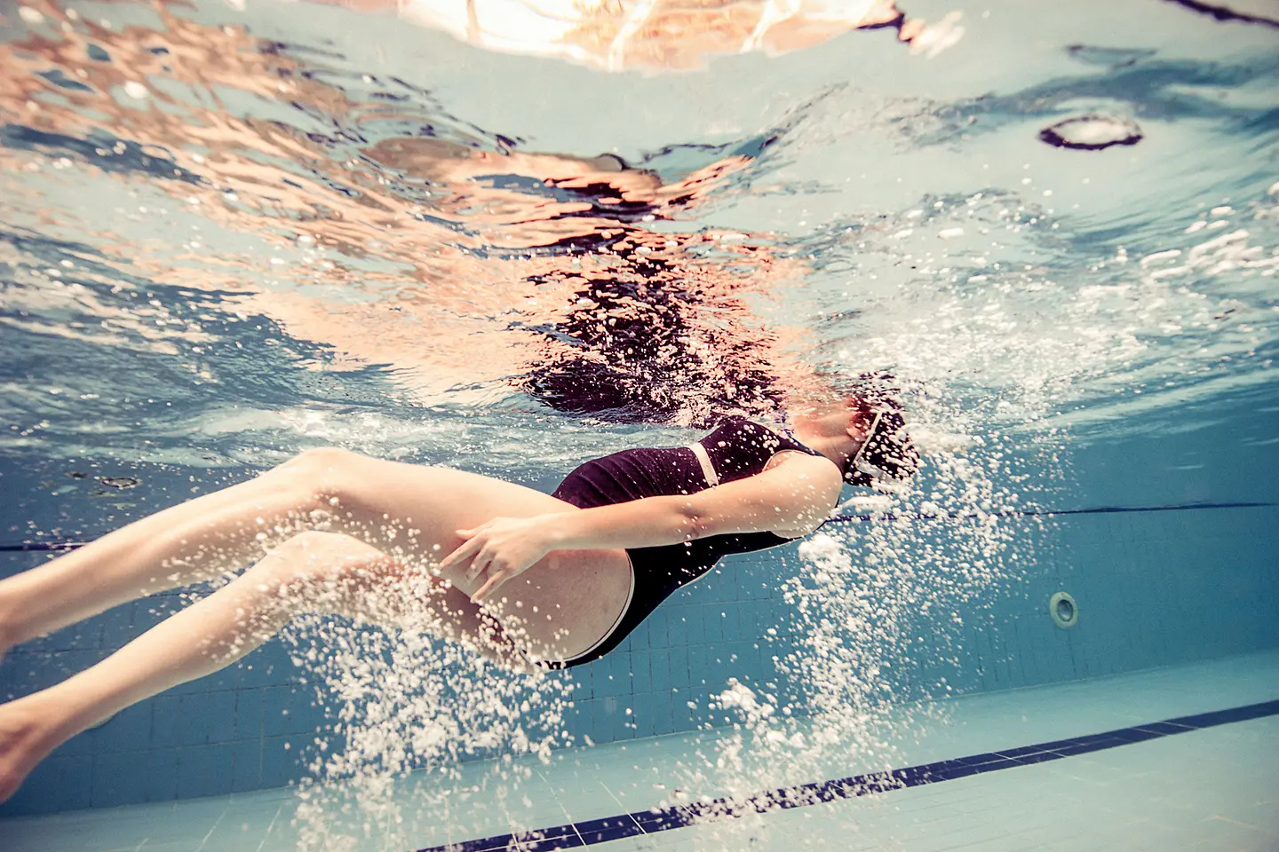Eine schwangere Frau in der 17. Schwangerschaftswoche unter Wasser in einem Schwimmbadbecken