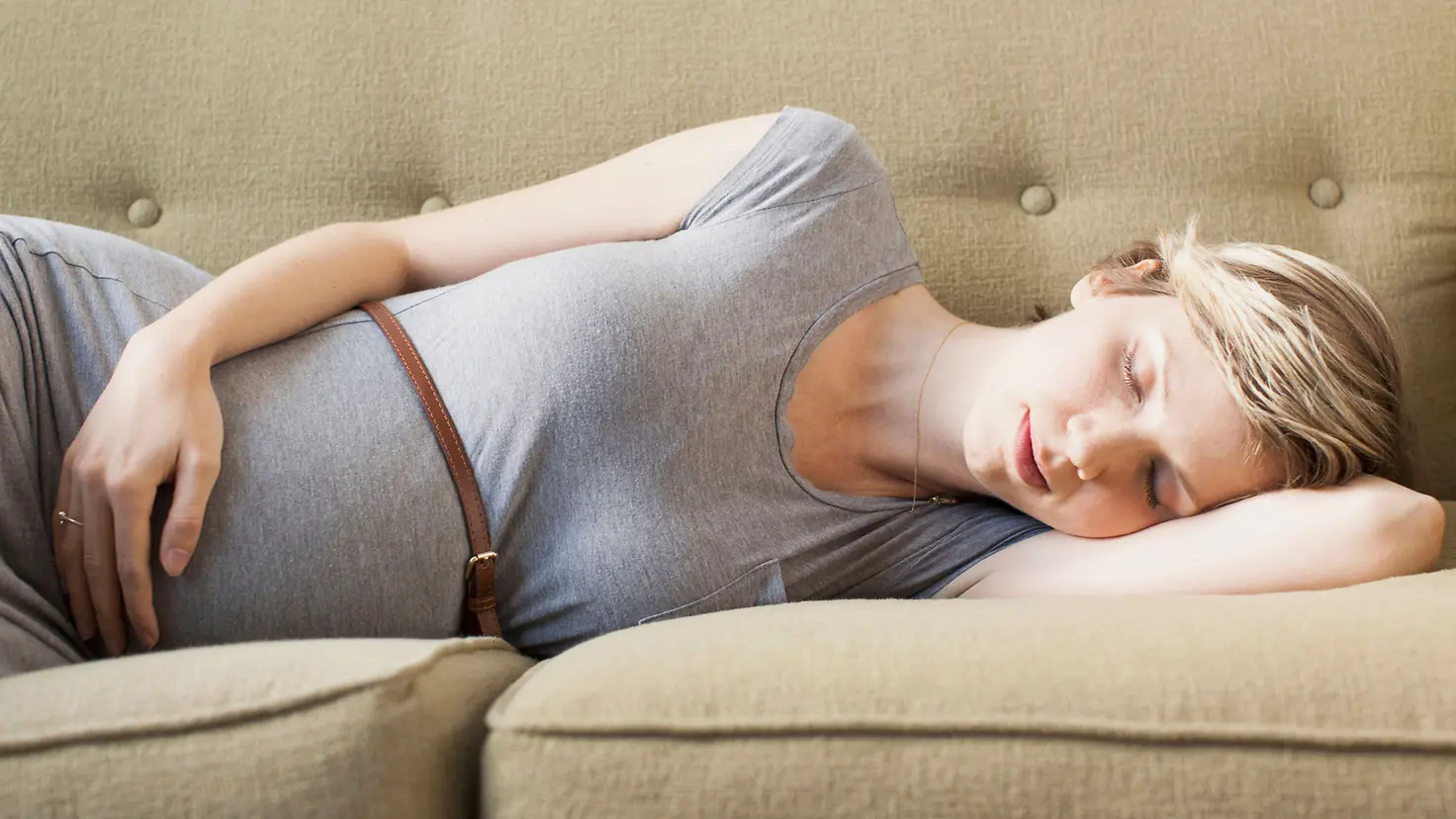 Frau in der 19.Schwangerschaftswoche schläft auf der Seite auf einer Couch