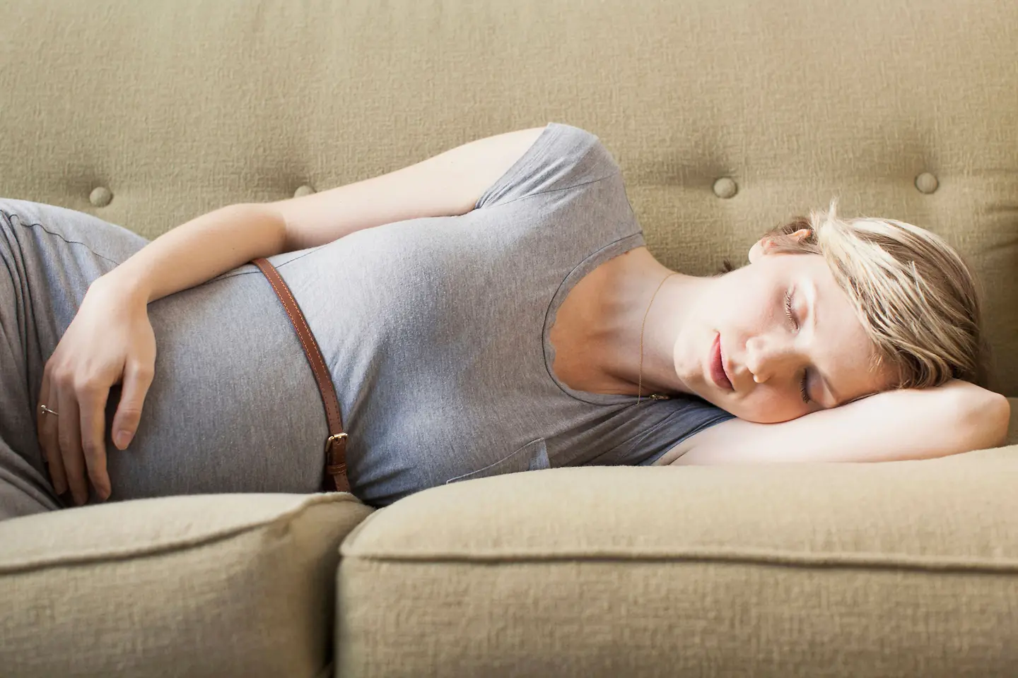 Frau in der 19.Schwangerschaftswoche schläft auf der Seite auf einer Couch