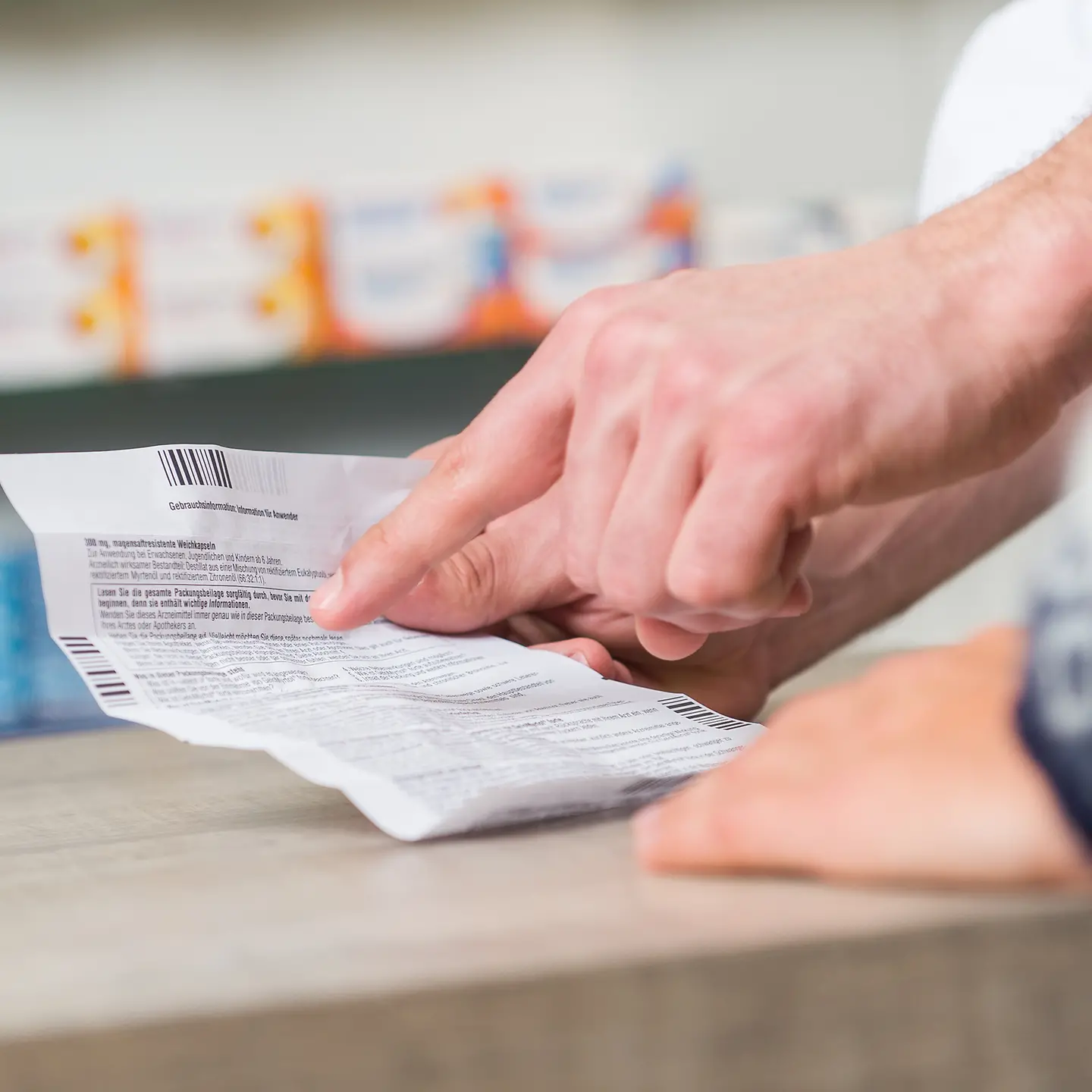Das Bild zeigt die Hand einer Person in einer Apotheke mit einem Beipackzettel.