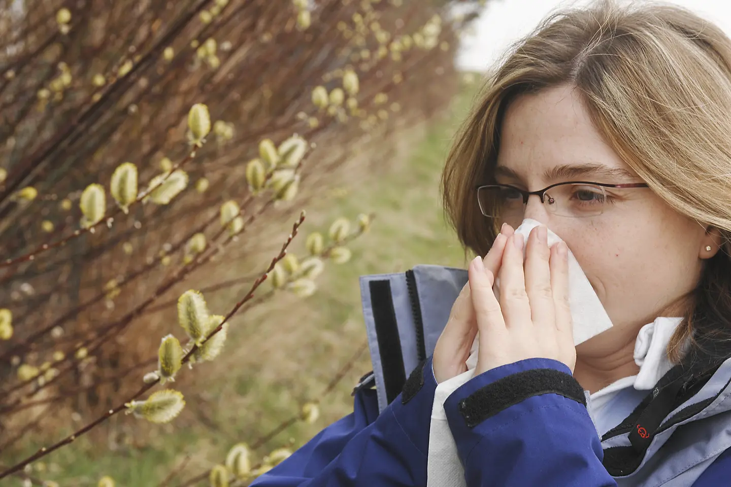Eine Frau mit Heuschnupfen schnäuzt ihre Nase.