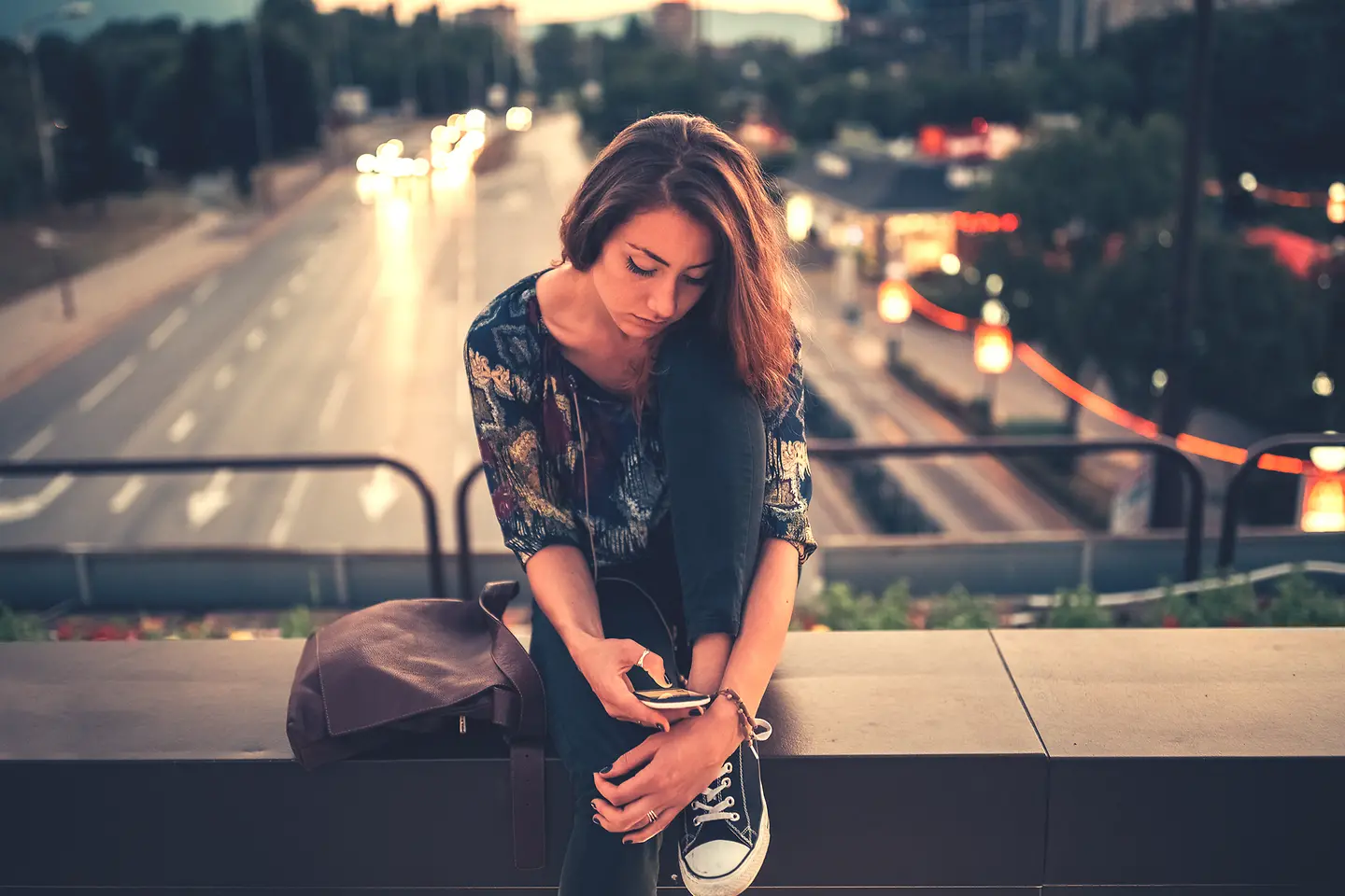 Eine Jugendliche schaut nachdenklich auf ihr Handy.